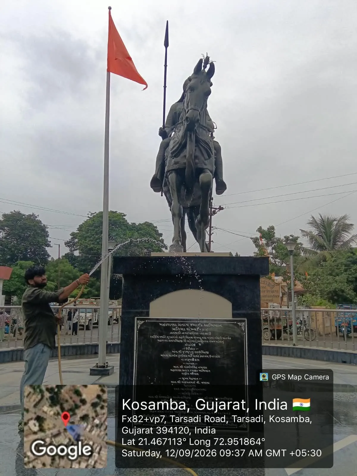 A worker cleaning the paved surroundings of an equestrian memorial statue at Kosamba
