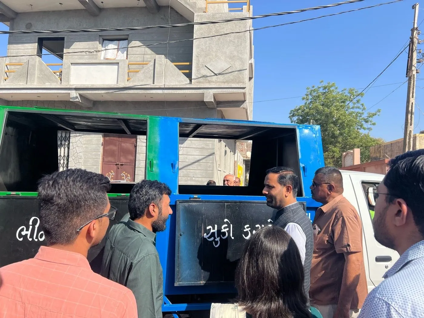 A group examining the open wet and dry compartments of a door-to-door collection vehicle during a discussion of its specifications