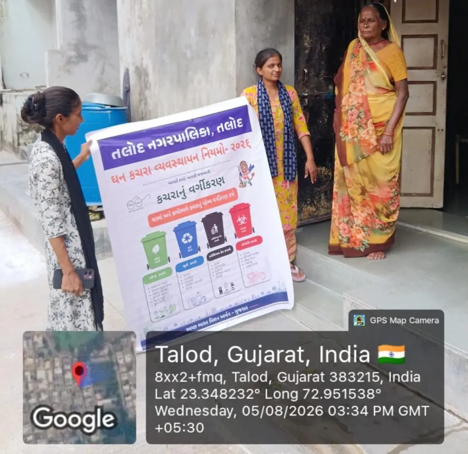 A J Kachrewala worker showing residents at their doorstep a Talod Nagarpalika poster explaining how to segregate household waste by bin colour