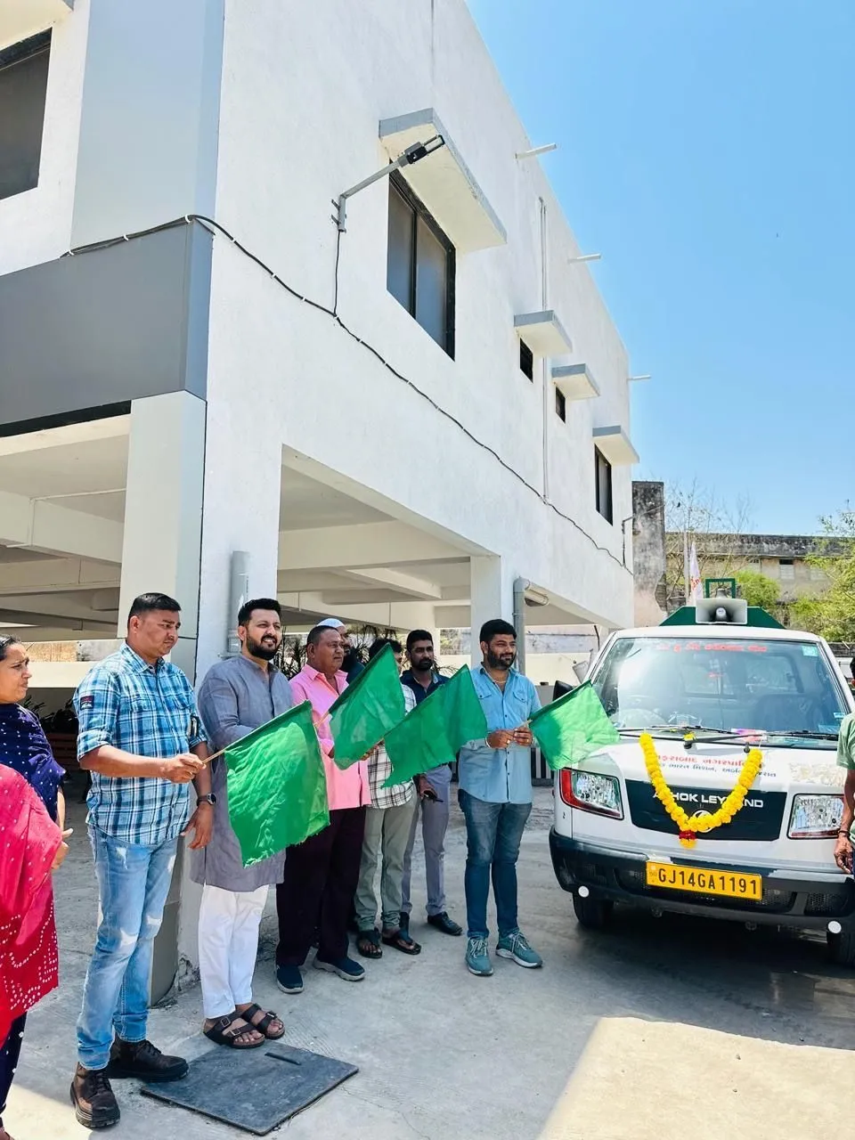 J Kachrewala staff in green uniform standing with a newly handed-over service vehicle outside an office building